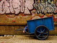 blue cart in front of graffeti brick wall